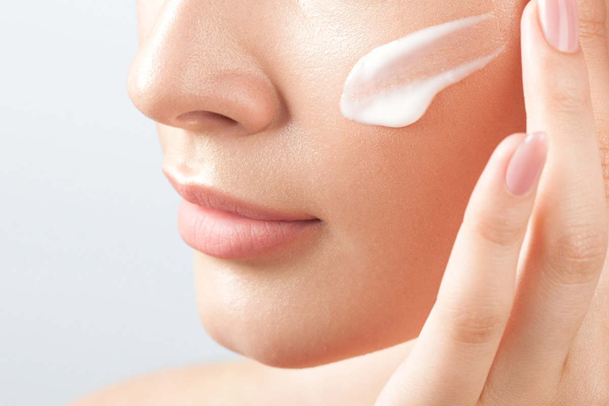 Close-up of caucasian female applying skincare cream to face